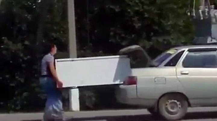 Kazakhstan man uses his girlfriend to carry a FRIDGE while running behind his car 