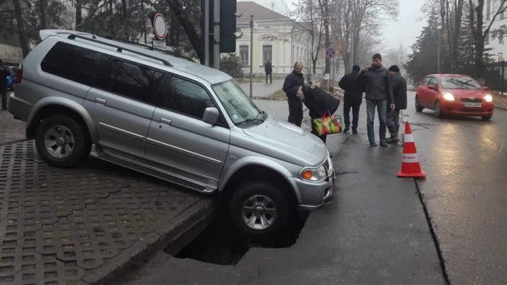 GROAPĂ URIAŞĂ în centrul Capitalei. O maşină, înghiţită de craterul care a apărut în asfalt (VIDEO/FOTO)