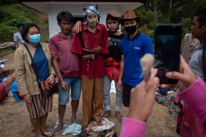 Ritual macabru pe o insulă din Indonezia: Oamenii își dezgroapă morții, le schimbă hainele și stau la o țigară cu ei (FOTO)