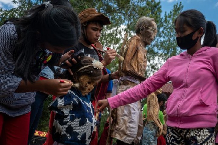 Ritual macabru pe o insulă din Indonezia: Oamenii își dezgroapă morții, le schimbă hainele și stau la o țigară cu ei (FOTO)