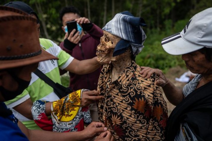 Ritual macabru pe o insulă din Indonezia: Oamenii își dezgroapă morții, le schimbă hainele și stau la o țigară cu ei (FOTO)