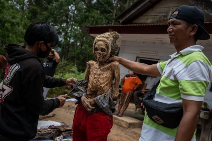 Ritual macabru pe o insulă din Indonezia: Oamenii își dezgroapă morții, le schimbă hainele și stau la o țigară cu ei (FOTO)