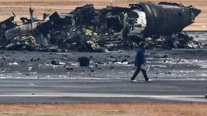 UN MORMAN DE FIARE! Imagini de pe aeroportul din Tokyo, cu epava înnegrită a avionului distrus ieri de flăcări. ŞOCAŢI, pasagerii au povestit cum s-au salvat