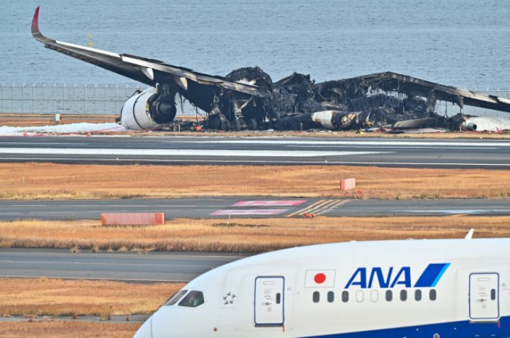 UN MORMAN DE FIARE! Imagini de pe aeroportul din Tokyo, cu epava înnegrită a avionului distrus ieri de flăcări. ŞOCAŢI, pasagerii au povestit cum s-au salvat