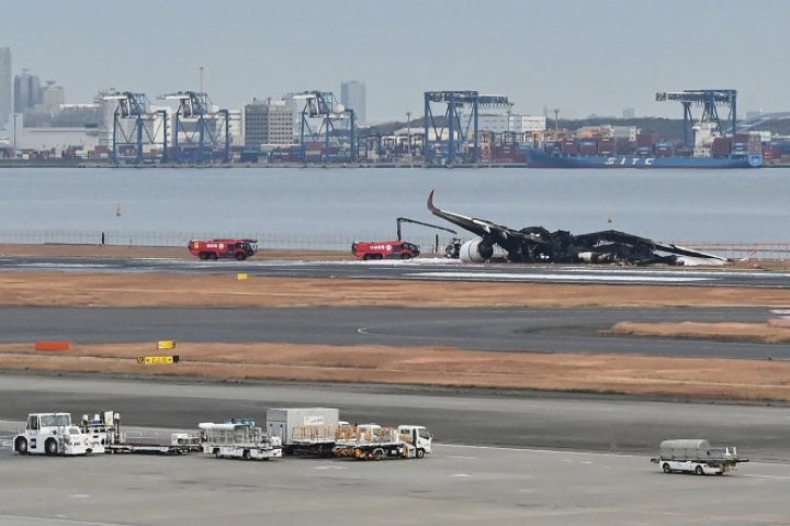 UN MORMAN DE FIARE! Imagini de pe aeroportul din Tokyo, cu epava înnegrită a avionului distrus ieri de flăcări. ŞOCAŢI, pasagerii au povestit cum s-au salvat